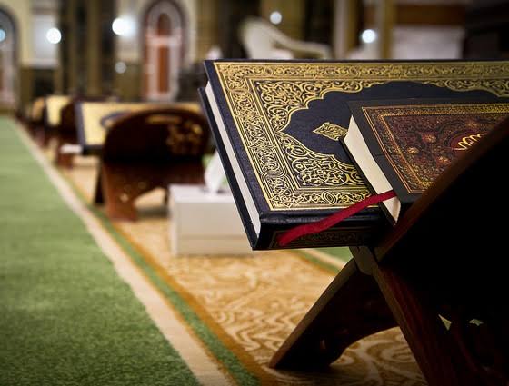 An open Qur&rsquo;an resting on a wooden stand inside the masjid